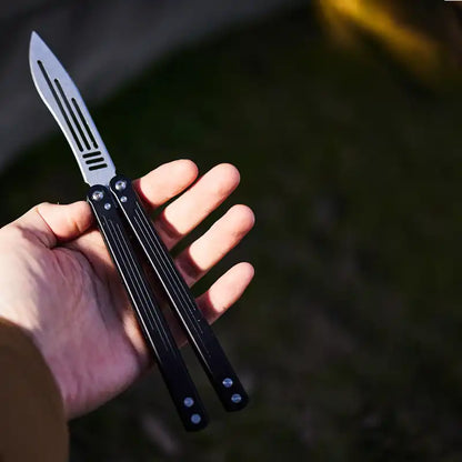 Armed Shark Balisong Trainer with black handle displayed in hand – training tool.
