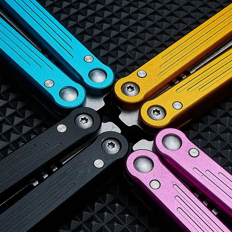 Close-up of Armed Shark Balisong Trainer handles in blue, gold, black, pink, and purple.