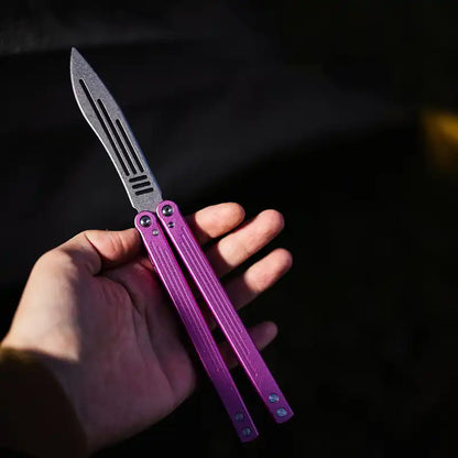 Armed Shark Balisong Trainer with pink handle shown in hand – practice ready.