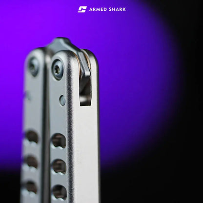 Close-up of the Armed Shark Inked Mako balisong trainer handle top with latch slot and crowned spine in silver finish.