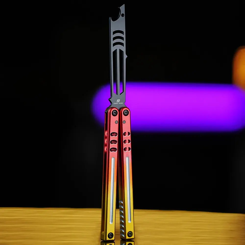 Armed Shark Inked Mako bottle-opener balisong trainer with dark training head and red-to-gold gradient handles, front view, studio background.
