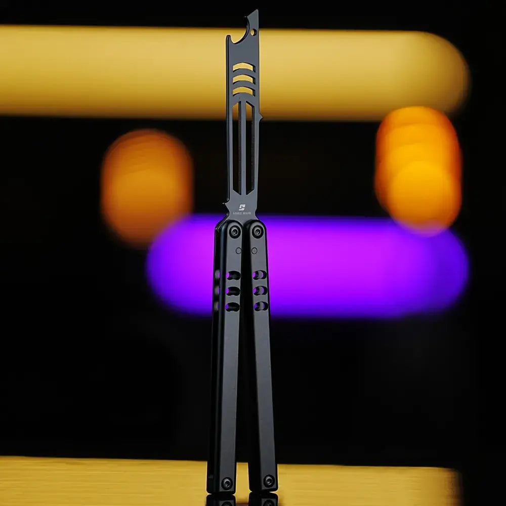 Armed Shark Inked Mako bottle-opener balisong trainer in matte black with dark training head, front view, studio bokeh background.