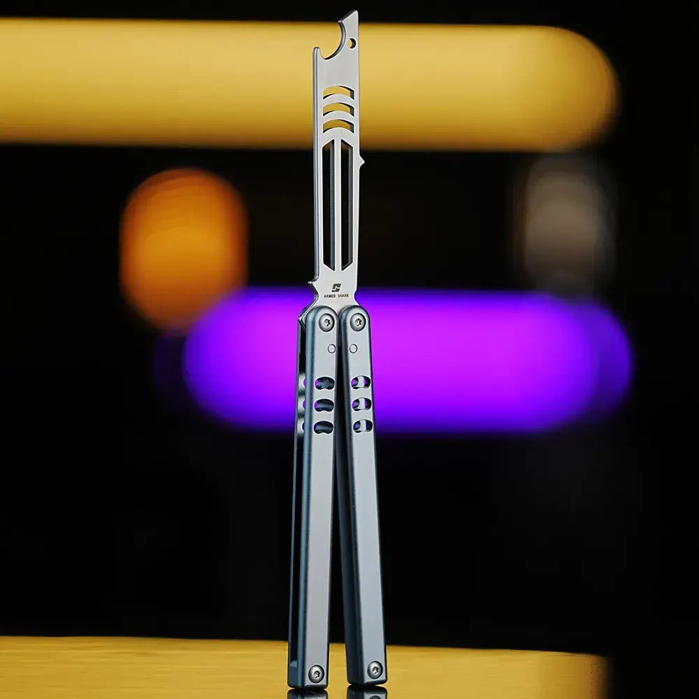 Armed Shark Inked Mako bottle-opener balisong trainer with silver training edge and gunmetal grey handles, front view, studio bokeh background.