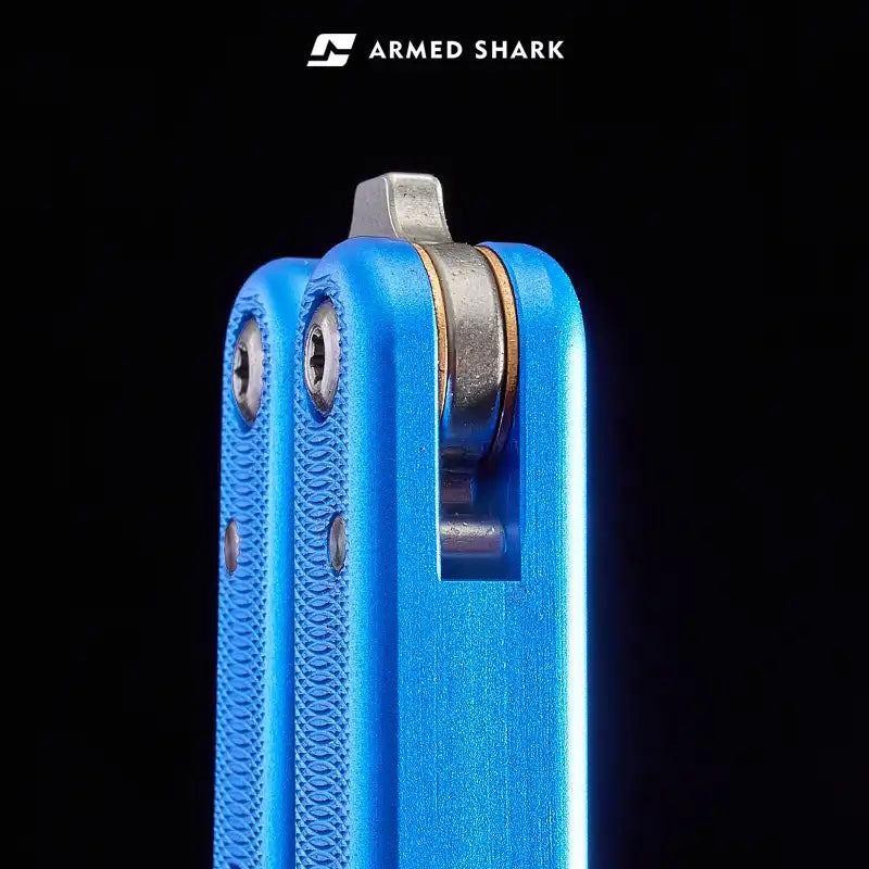 Close-up of Armed Shark Squidtrainer V4 7075 aluminum balisong trainer handle top showing latch slot and hardware, blue anodized finish.